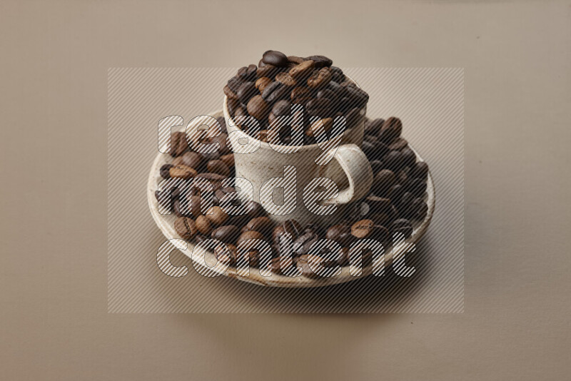 A beige pottery cup full of roasted coffee beans on beige background