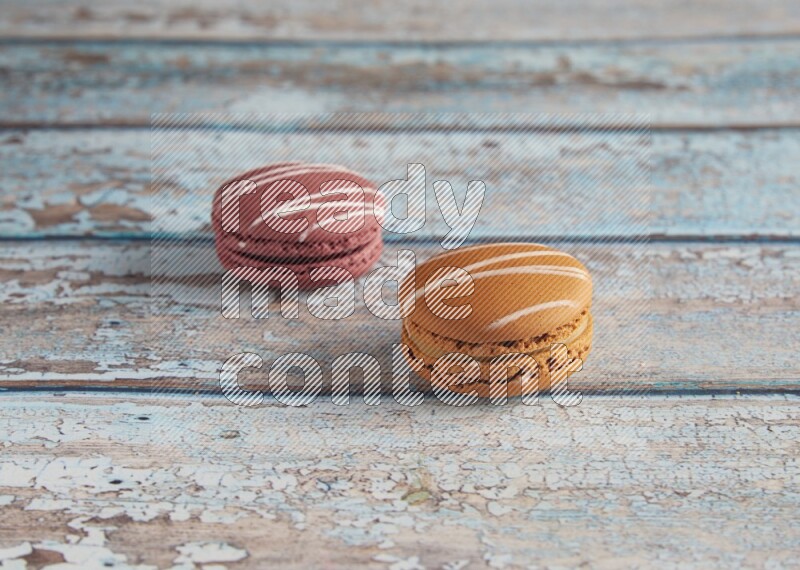 45º Shot of of two assorted Brown Irish Cream, and Red Poppy Flower macarons  on light blue background