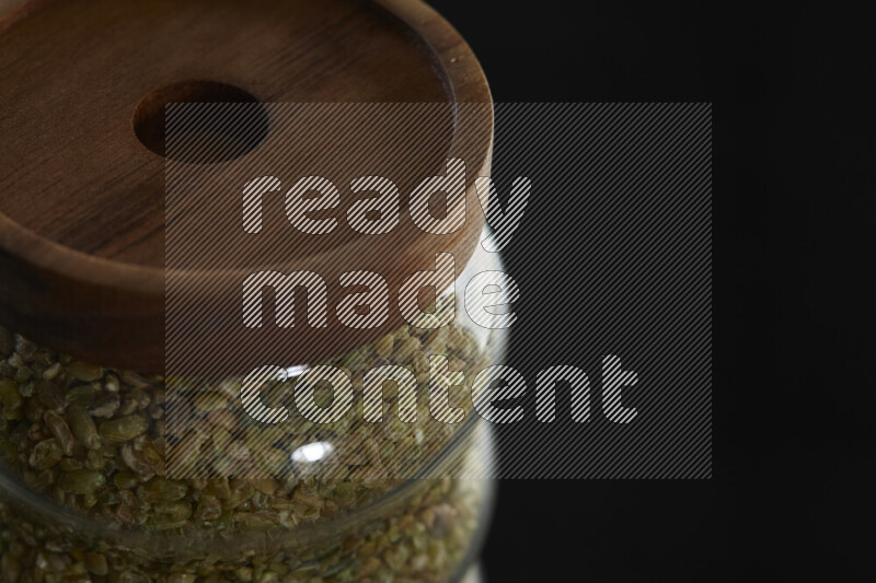 Freekeh in a glass jar on black background