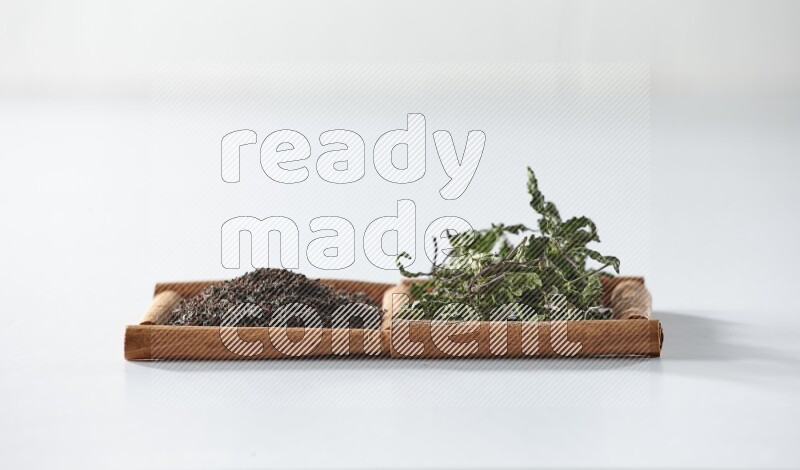 2 squares of cinnamon sticks full of black tea and dried mint leaves on white flooring