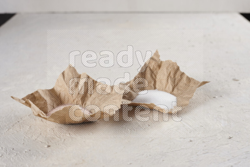 2 crumpled pieces of paper full of pink himalayan salt and white salt on white background