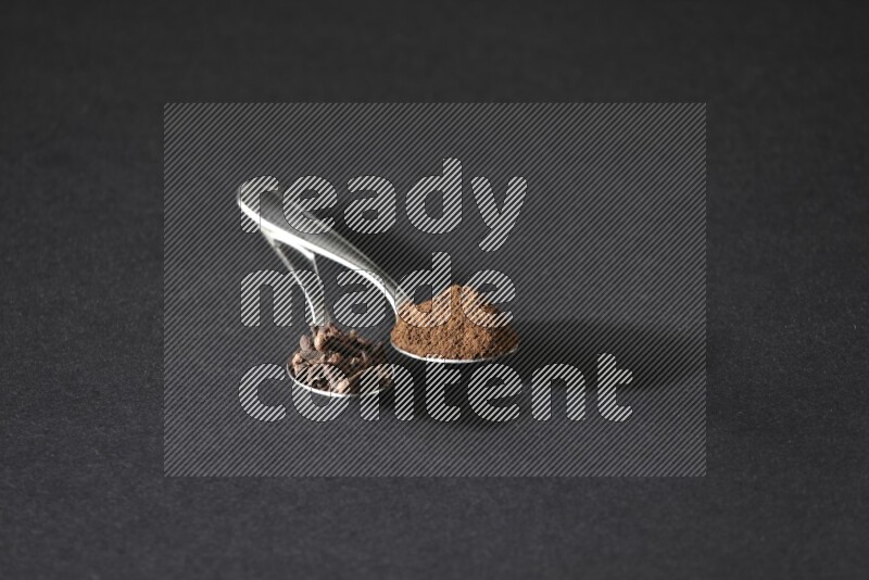 ملعقتان معدنيتان، إحداهما ممتلئة بحبوب القرنفل والأخرى ببودرة القرنفل، على خلفية سوداء