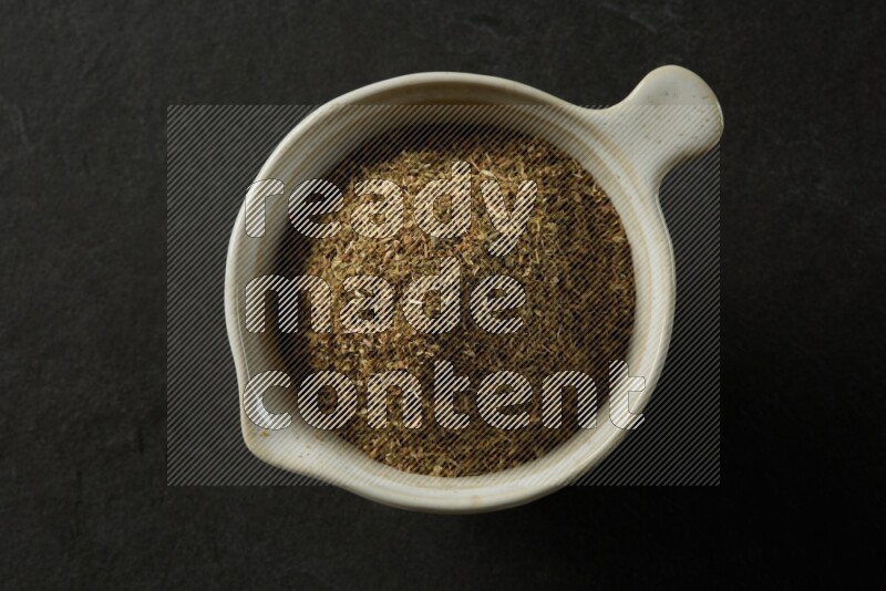 white ceramic round sauce bowl filled with herbs on grey textured countertop