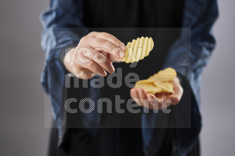 Woman in abaya holding different kinds of snacks in different positions
