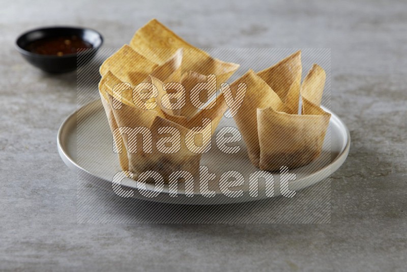wonton cups with soy sauce ramkin on grey ceramic plate on grey textured counter top