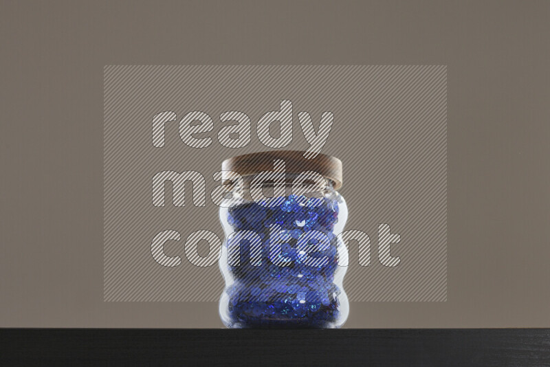 Sequins in a glass jar on black background
