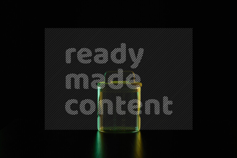 Glassware with rim light in green and yellow against black background