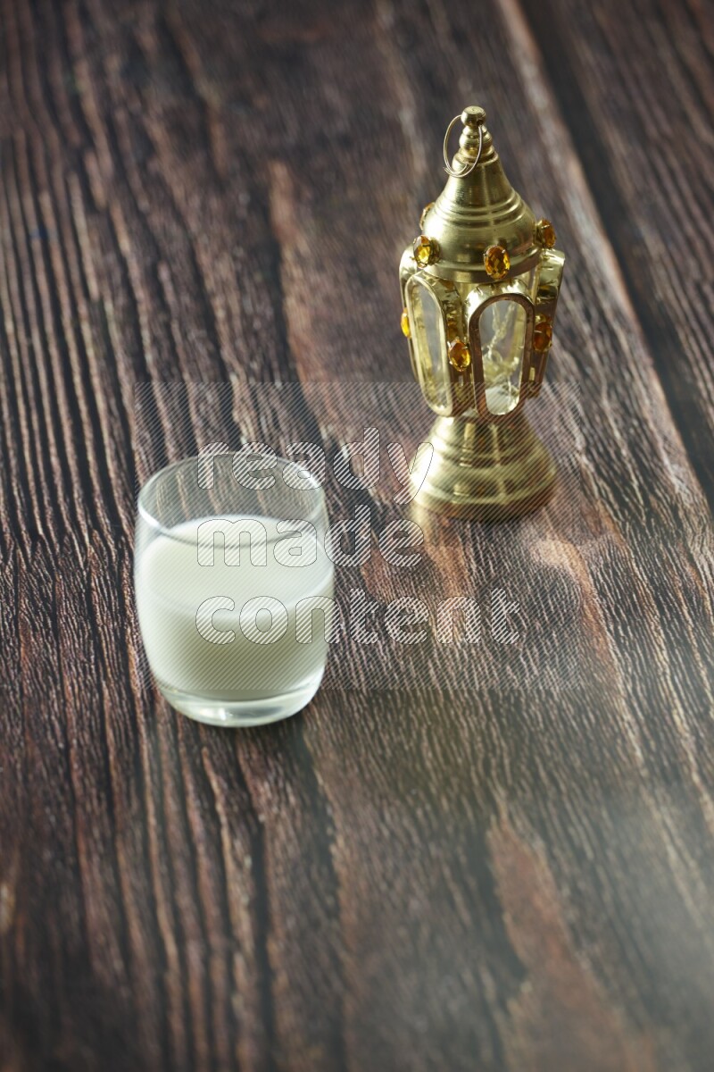 فانوس ذهبي مع مشروبات مختلفة وتمر ومكسرات وسبحة صلاة وقرآن على خلفية خشبية بنية