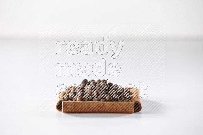 A single square of cinnamon sticks full of allspice on white flooring