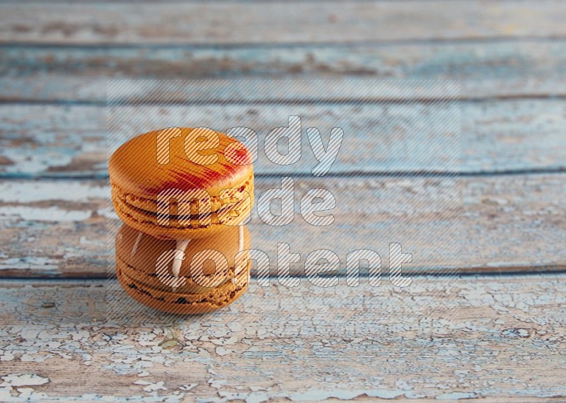 45º Shot of of two assorted Brown Irish Cream, and Orange Exotic macarons on light blue background