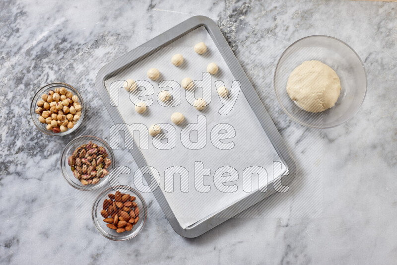 Ghoriba step by step with its ingredient, flour, powdered sugar, ghee and nuts on grey marble background