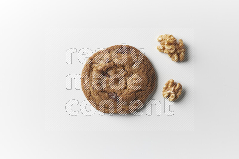 A single chocolate chips cookie with walnuts beside it on a white background