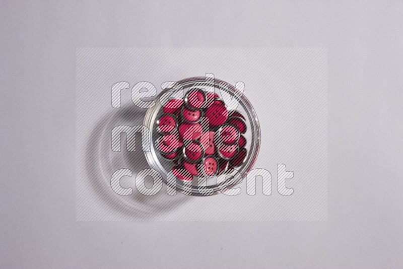 Colored buttons in a glass bowl on grey background