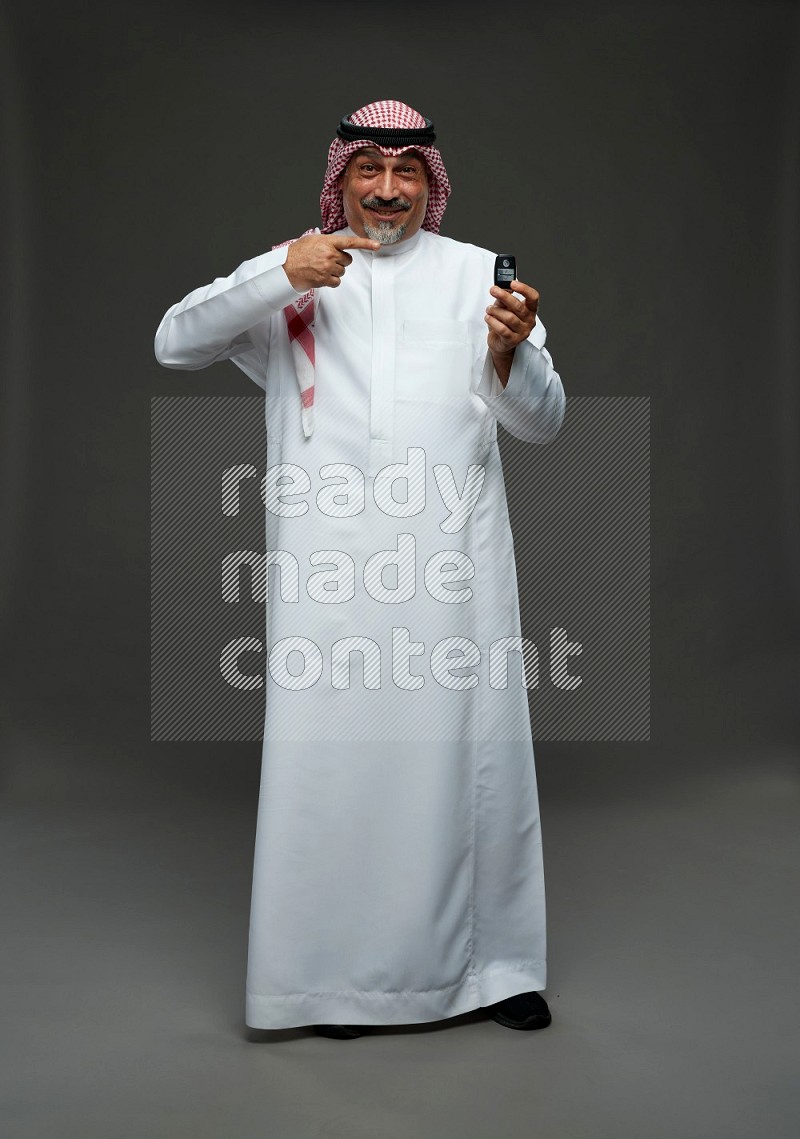 Saudi man with shomag Standing holding car key on gray background