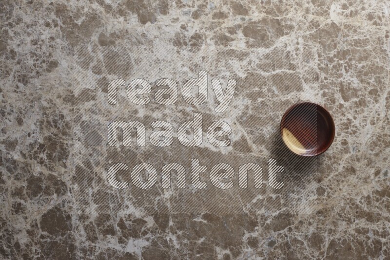 A wooden bowl on beige marble background