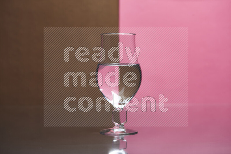 The image features a clear glassware filled with water, set against brown and pink background