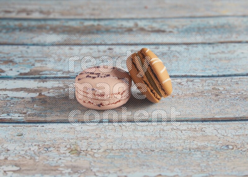 45º Shot of of two assorted Brown Irish Cream, and pink orange blossom  macarons on light blue background