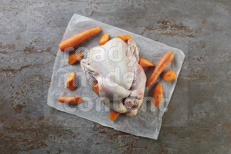 whole raw chicken on a parchment paper direct on a rustic grey background