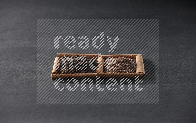 2 squares of cinnamon sticks full of flaxseeds and cloves on black flooring