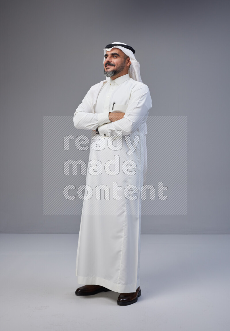 Saudi man Wearing Thob and white Shomag standing with crossed arms on Gray background