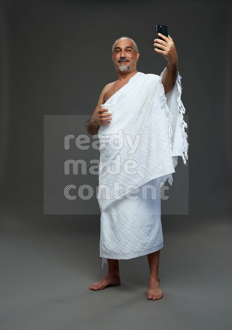 A man wearing Ehram Standing taking selfie on gray background