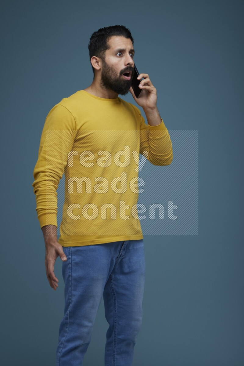 A man having a calling in a blue background wearing a yellow shirt