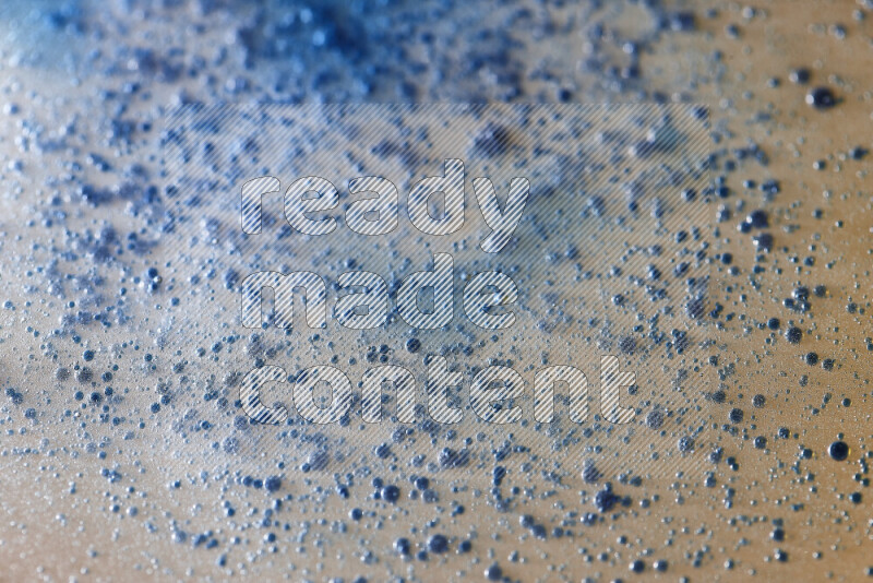 Close-ups of abstract blue watercolor drops on oil Surface on yellow background
