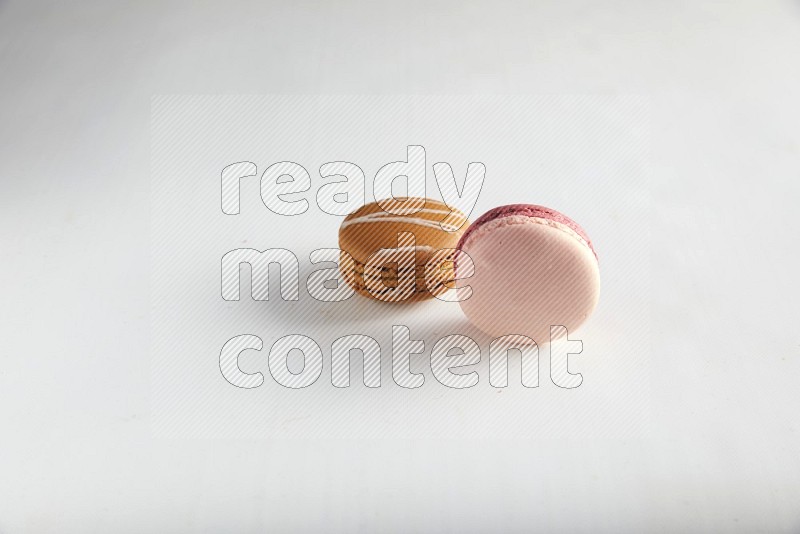 45º Shot of of two assorted Brown Irish Cream, and Pink Litchi Raspberry macarons on white background