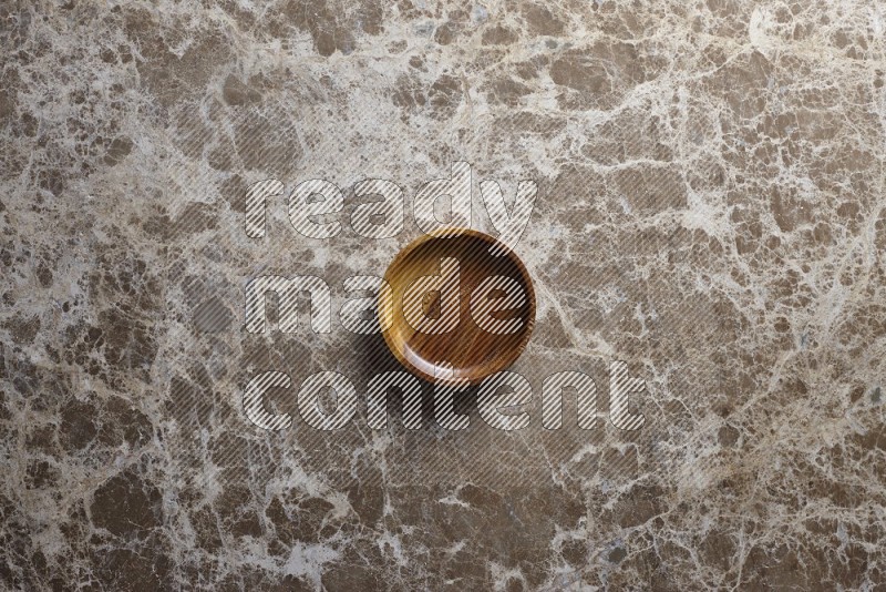 A wooden bowl on beige marble background