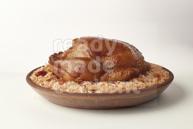 red basmati Rice with whole roasted chicken on a pottery plate direct on white background