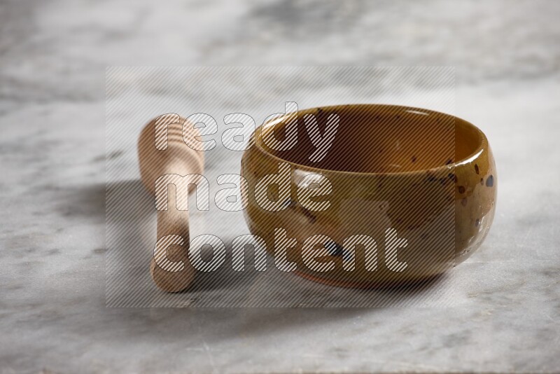 Multicolored pottery bowl with wooden honey dipper on the side on grey marble background