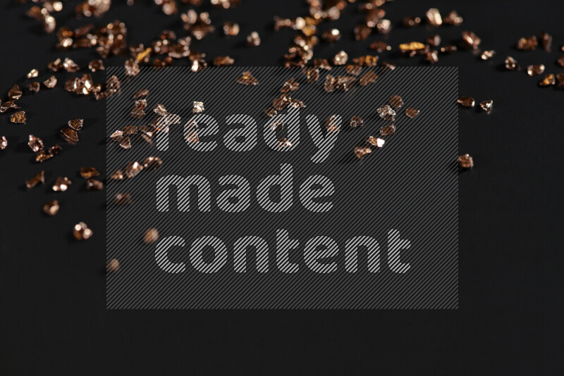 قطع زجاجية برونزية لامعة متناثرة على خلفية سوداء