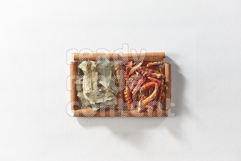 مربعان من أعواد القرفة ممتلئان بالفلفل الحار المجفف وأوراق الغار علي خلفية بيضاء