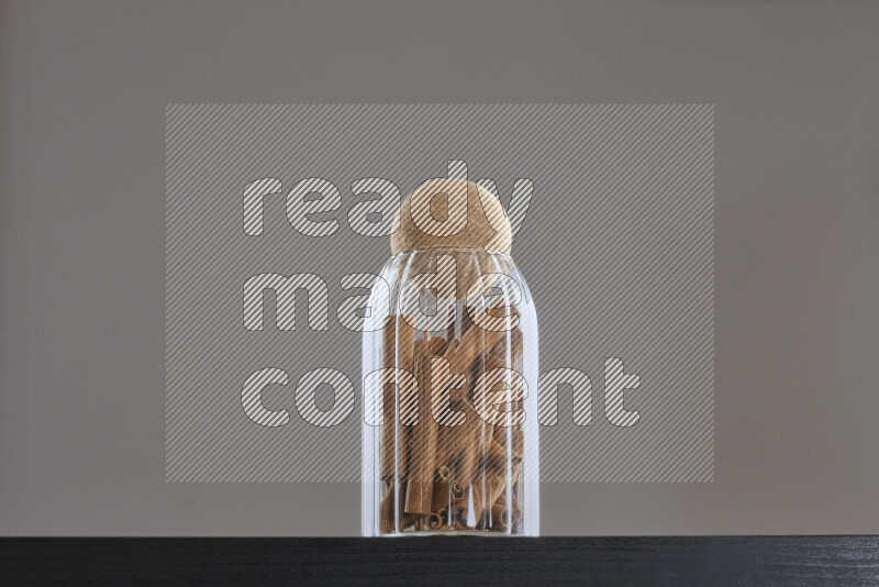Cinnamon sticks in a glass jar on black background