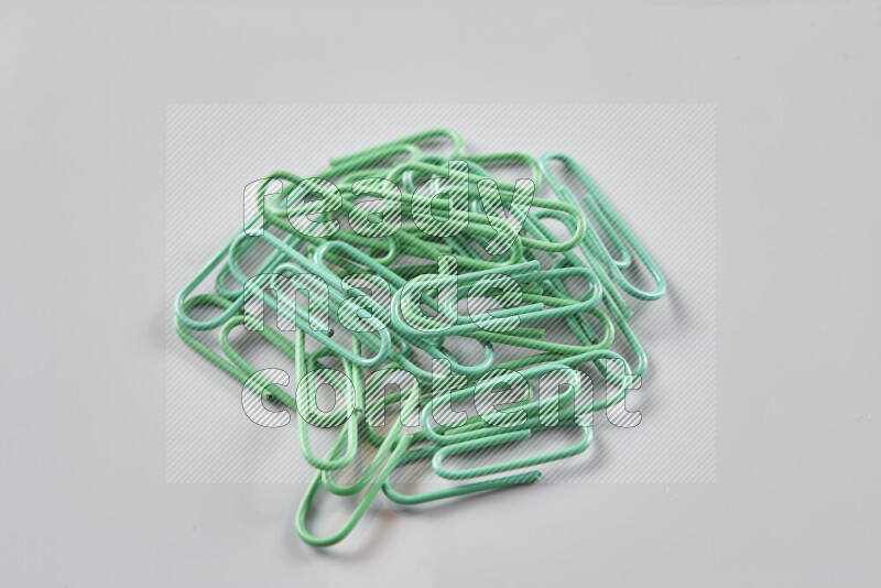 Green paper clips isolated on a grey background