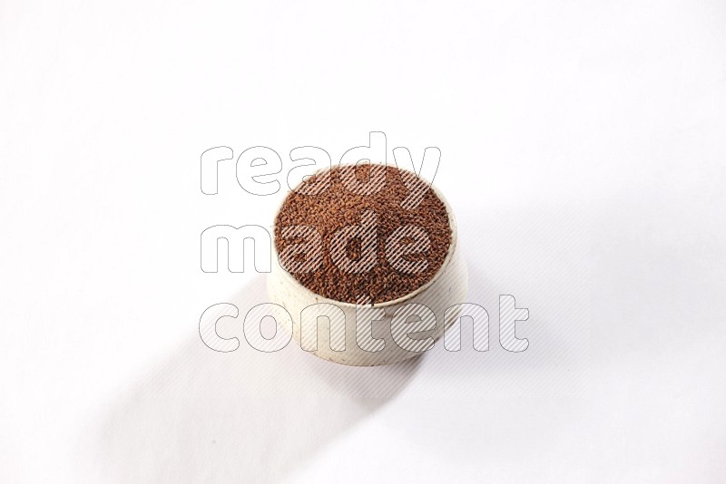 A beige pottery bowl full of garden cress seeds on a white flooring