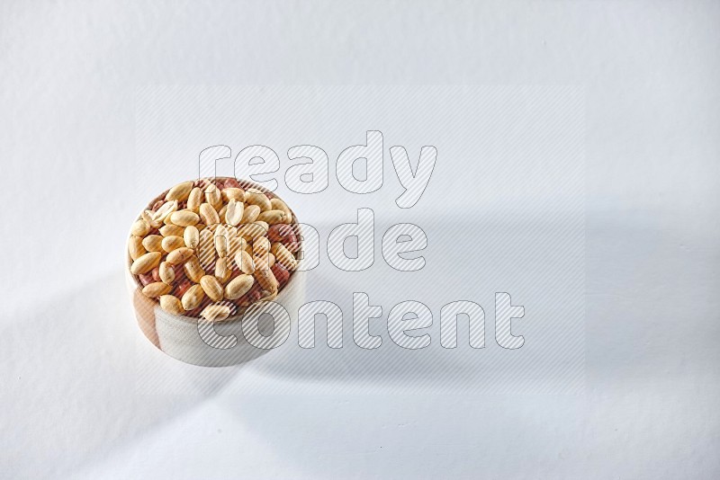 A beige ceramic bowl full of peeled peanuts on a white background in different angles