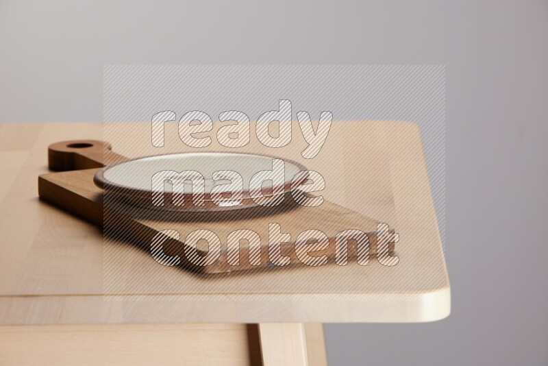 multi-colored pottery Plate placed on a  wooden rectangular cutting board on the edge of wooden table