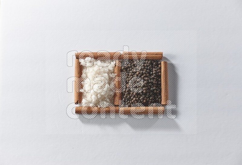 2 squares of cinnamon sticks full of black pepper and white salt on white flooring