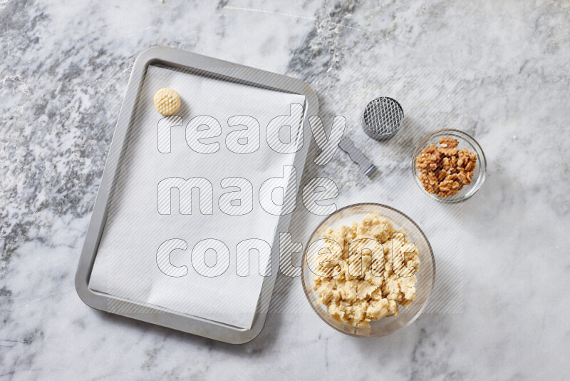 كحك خطوة بخطوة بمكوناته سمن، سكر، دقيق، سمسم، خميرة، ماء ونكهة الكحك على خلفية رخام رمادي