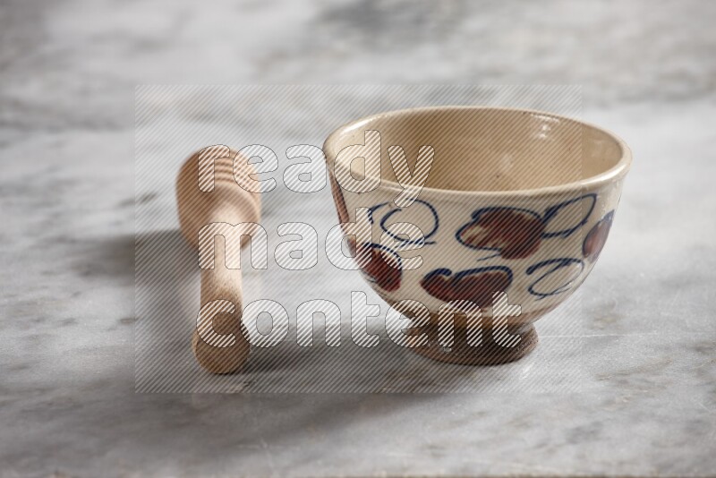 Decorative pottery bowl with wooden honey dipper on the side on grey marble background