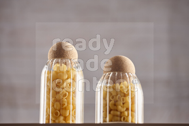 Raw pasta in glass jars on beige background