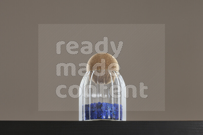 Sequins in a glass jar on black background