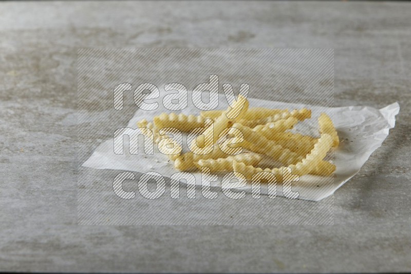 crinkle fries on parchment paper on grey textured counter top