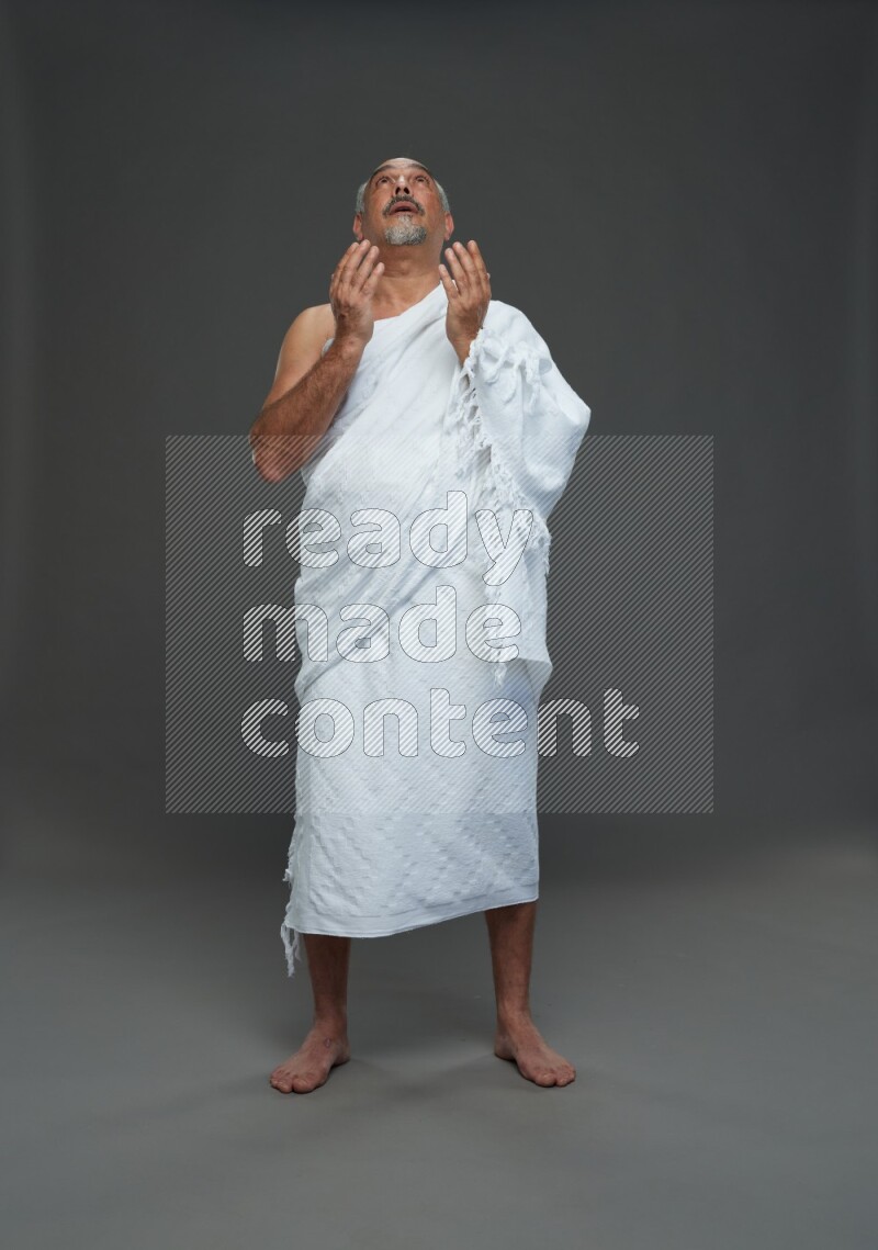 A man wearing Ehram Standing dua'a on gray background