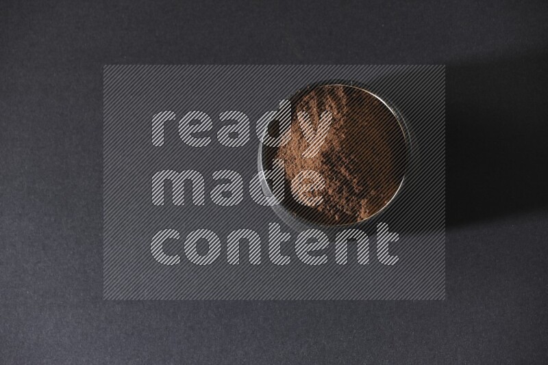 وعاء فخاري أسود ممتلئ ببودرة القرنفل علي خلفية سوداء