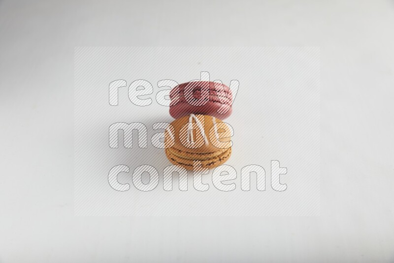45º Shot of of two assorted Brown Irish Cream, and Red Velvet macarons on white background