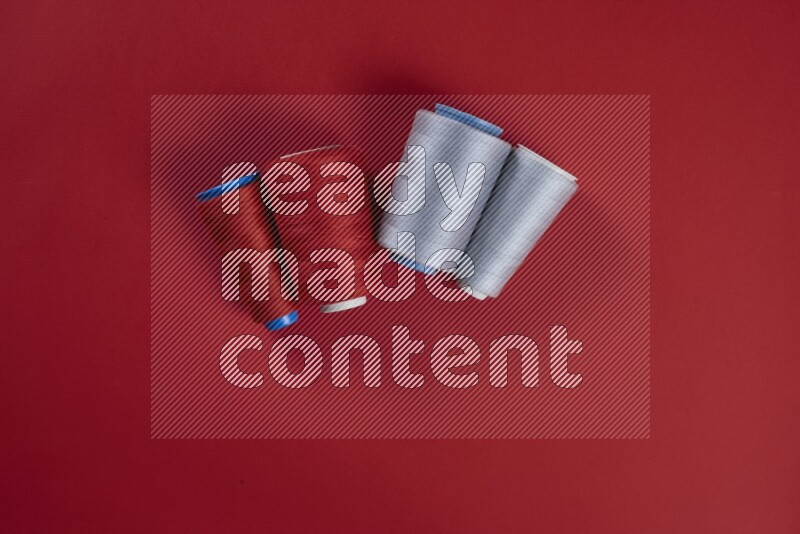 مجموعة من أدوات الخياطة والتفصيل رمادية اللون على خلفية حمراء