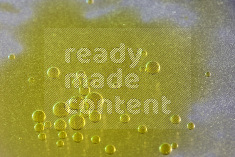 Close-ups of abstract yellow watercolor drops on oil Surface on white background