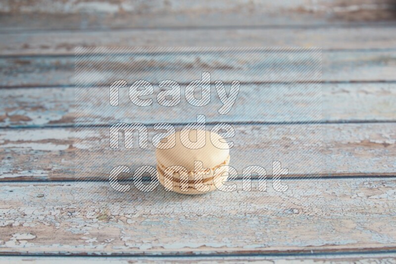45º Shot of White Caramel fleur de sel macaron on light blue wooden background
